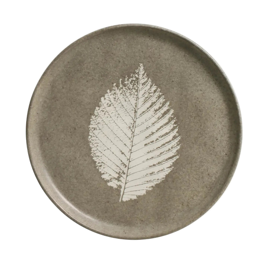 Seiva Dessert Plate is a round ceramic plate with a white leaf design on a beige background