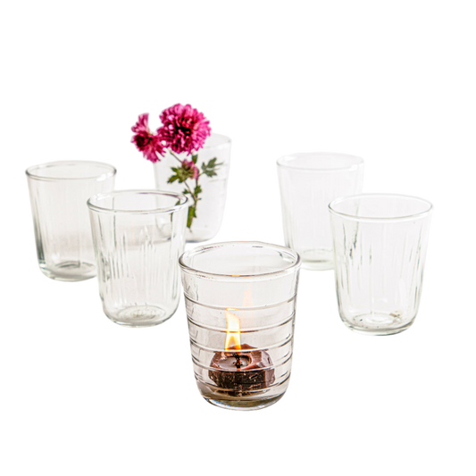 Short, clear glass tumblers with textured details on the sides for drinking or displaying