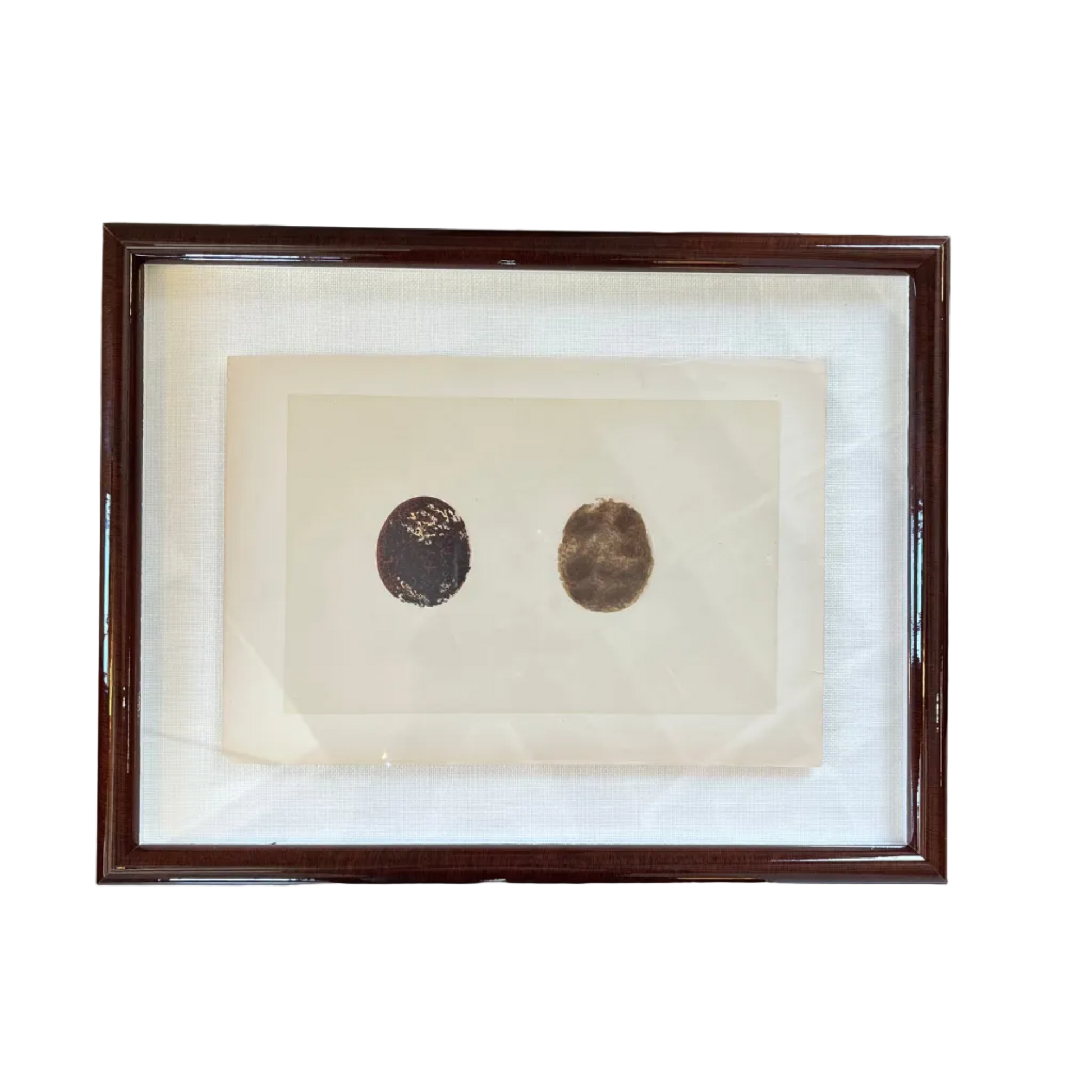 Framed artwork with two circular objects on a white background