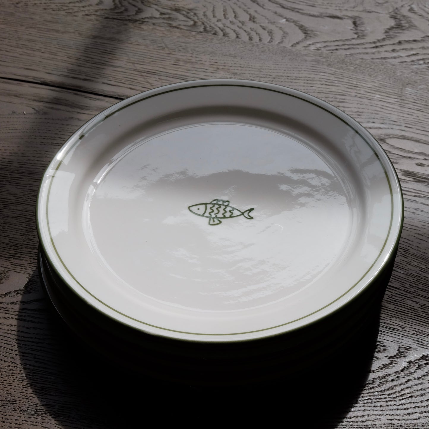 white ceramic dessert plate with green fish and trim detail