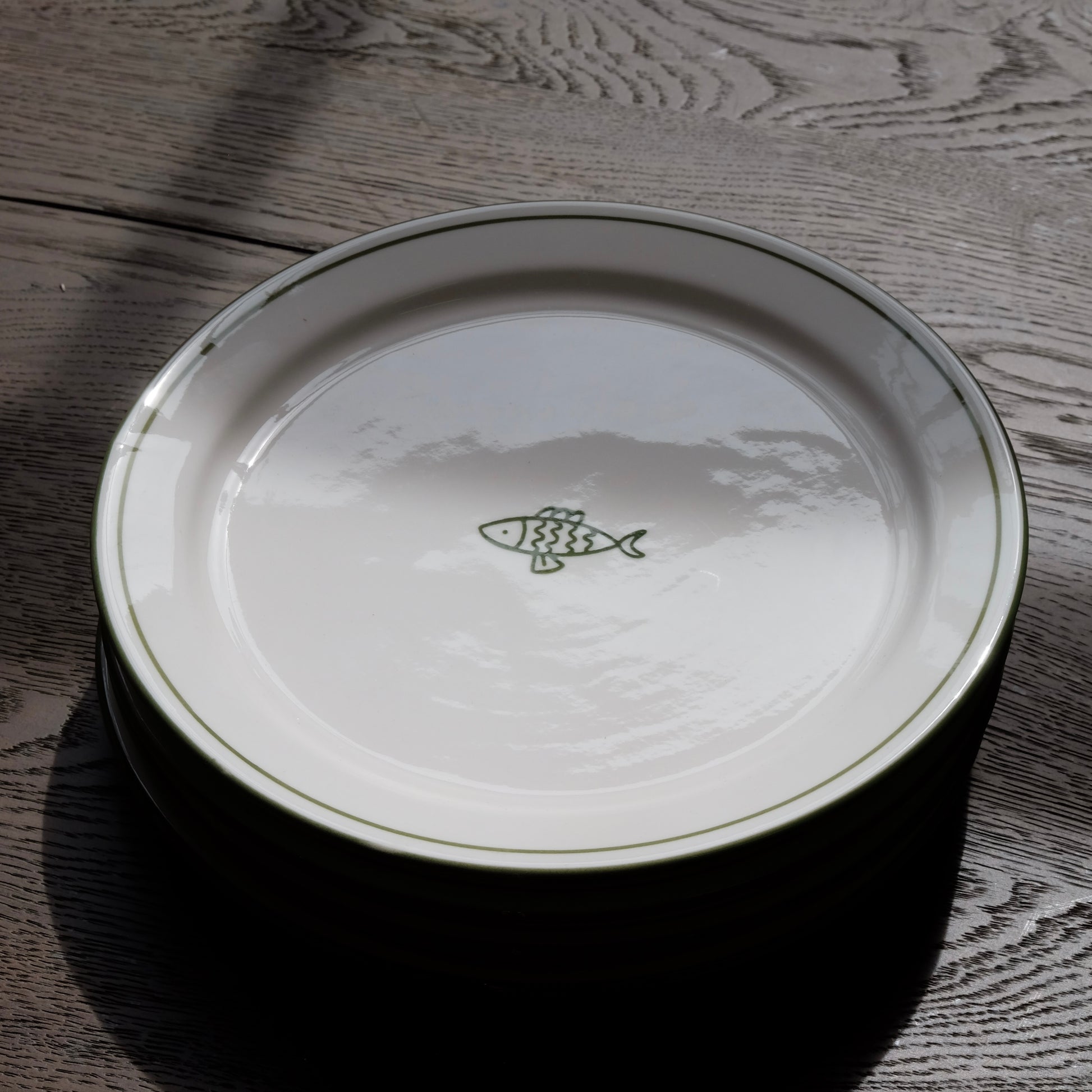 white ceramic dessert plate with green fish and trim detail