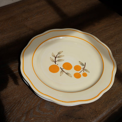 ivory ceramic dinner plate with citrus and orange trim detail and scalloped edges 