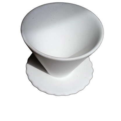 white ceramic pour over coffee dripper with a scalloped base and subtle brown speckles